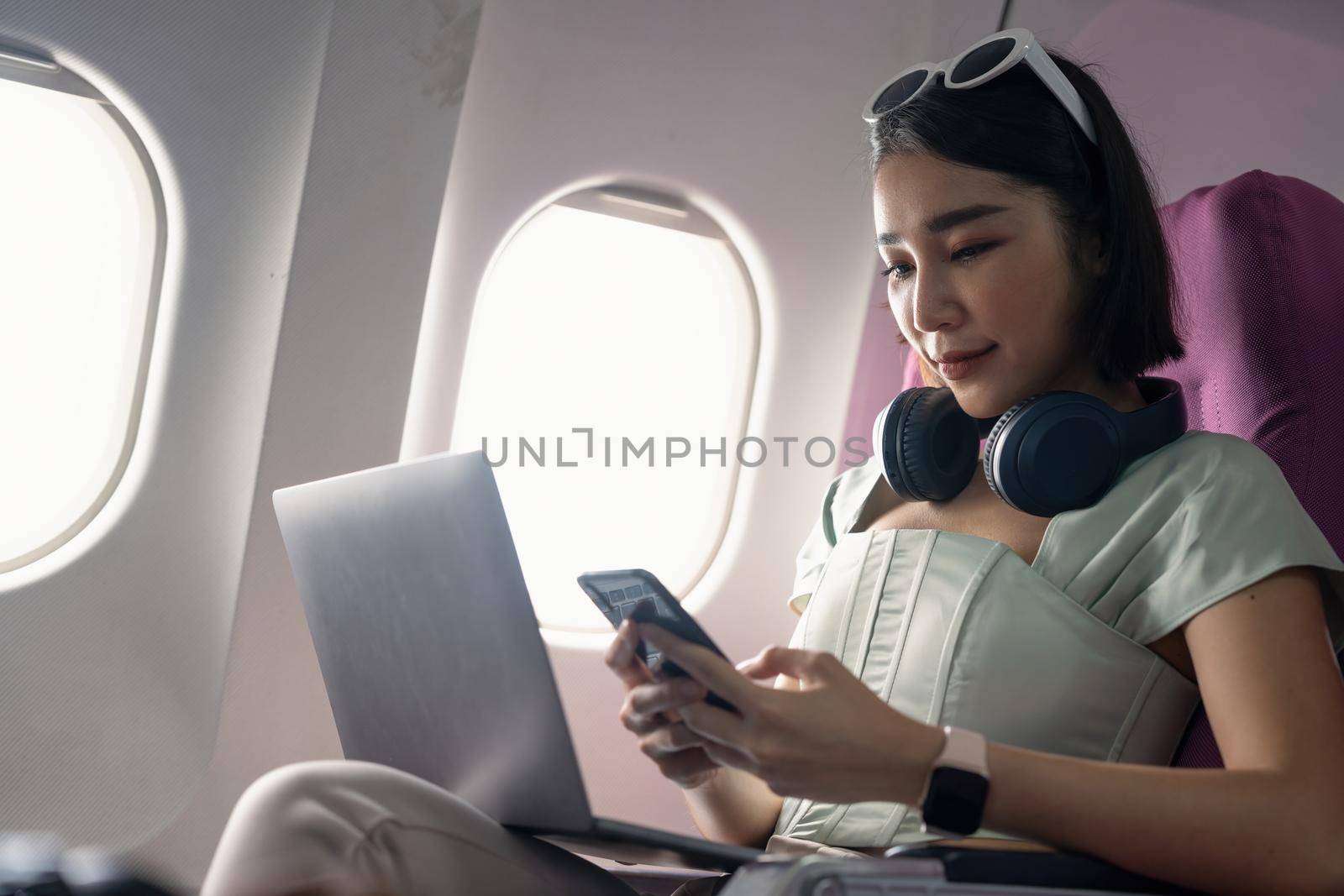 Attractive asian woman passenger of airplane read news from networks via smartphone and wifi on board. tourism traveler concept