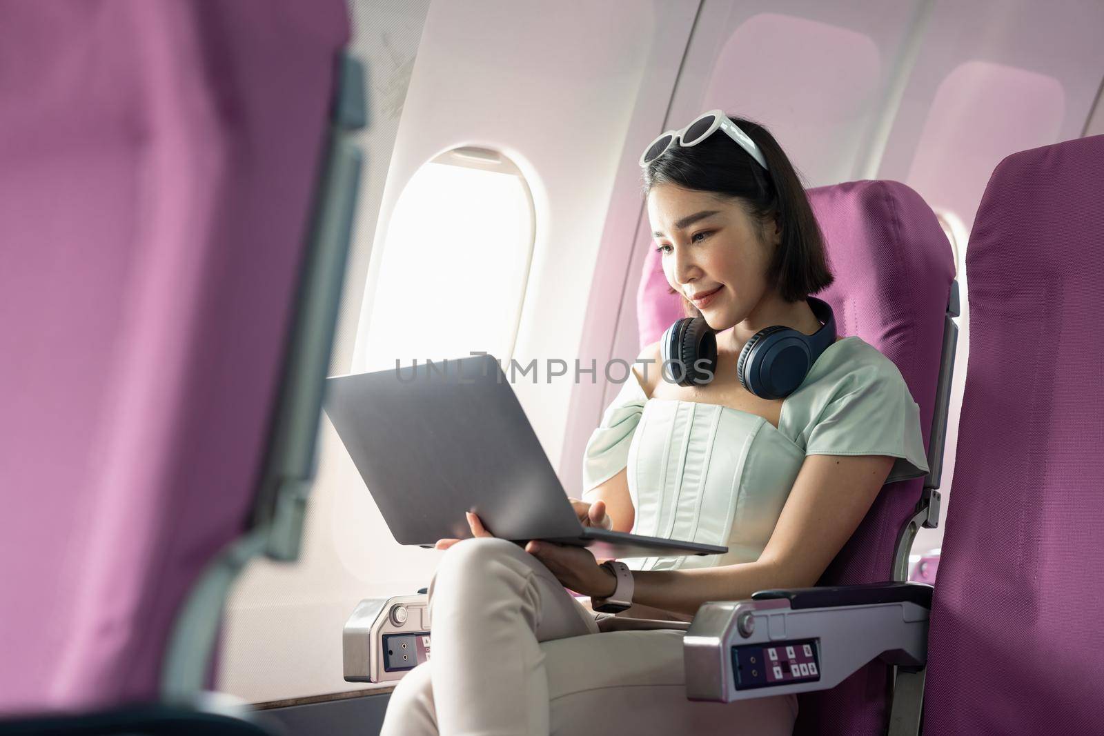 Attractive asian woman passenger of airplane using laptop computer and wifi on board. tourism traveler concept. by nateemee