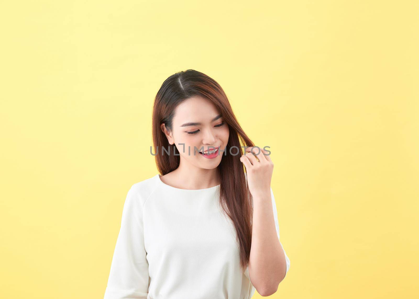 Beauty woman touch her long hair isolated on yellow background, asian beauty 