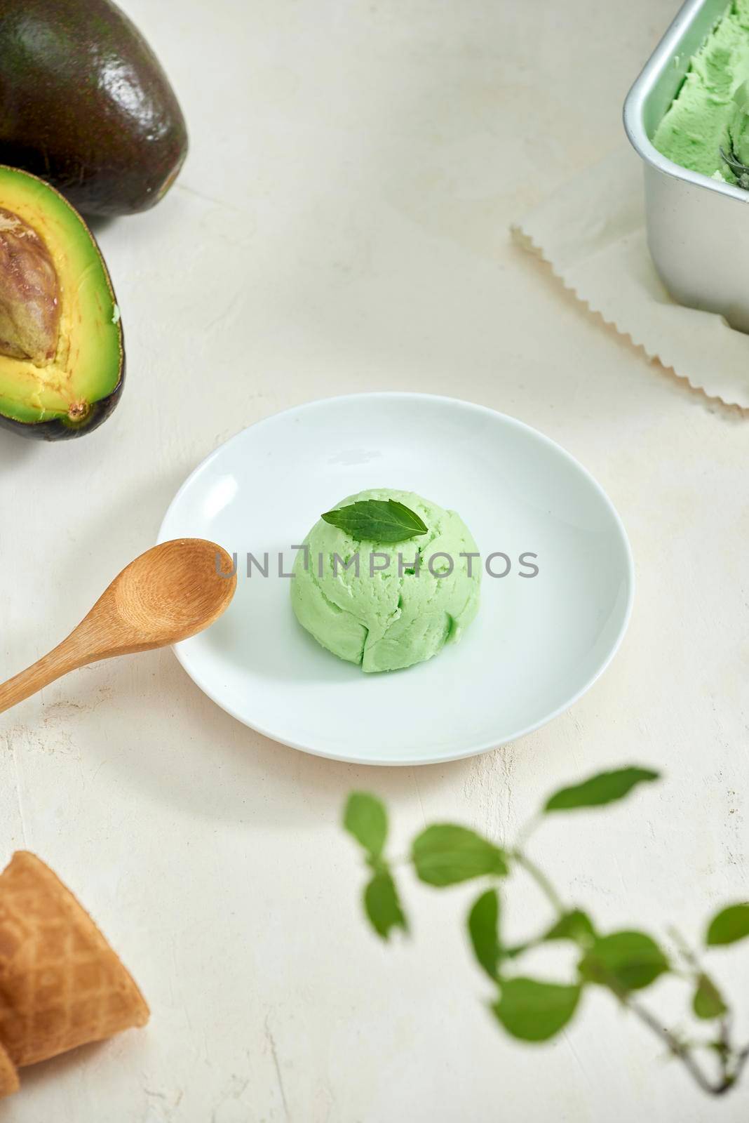 Avocado ice cream balls on a white plate, a spoon on a white background. by makidotvn