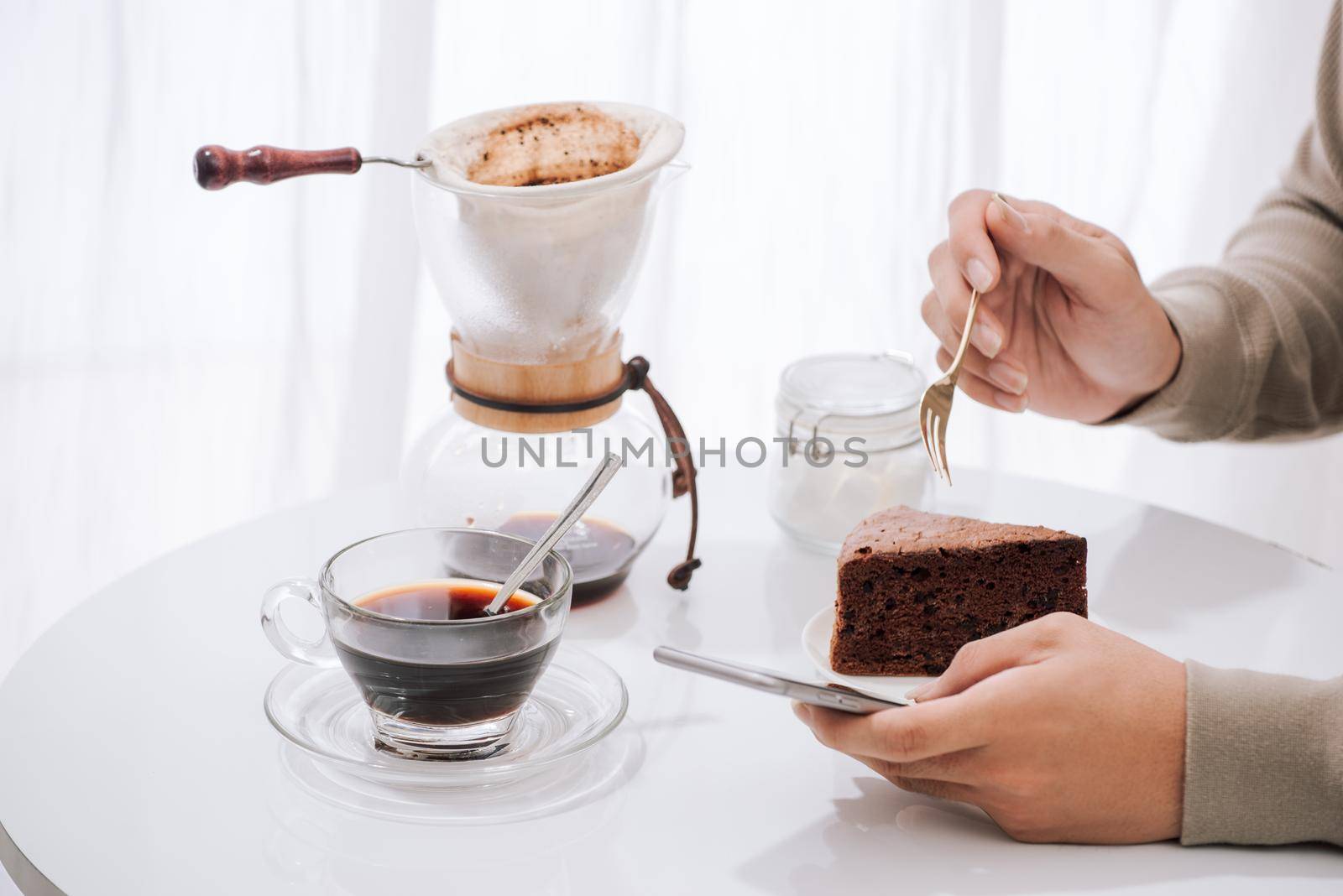 A young man is sitting in coffee shop drinking coffee and eating cake. With copy space