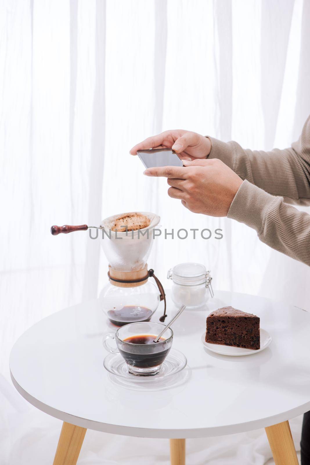 Handsome asian taking photo of chocolate cake and milk at coffee shop. Dessert or food photography hobby. Smartphone or mobile phone photography habit concept. 