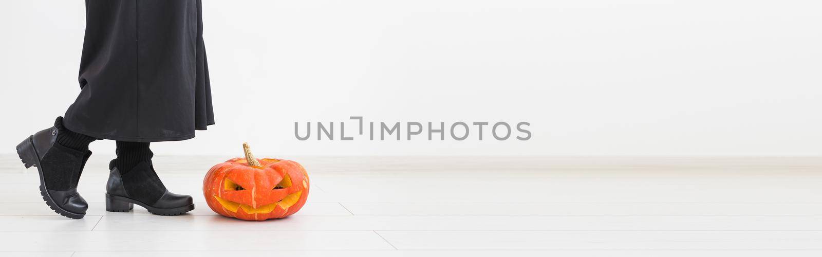 Banner halloween concept - Anonymous witch with pumpkin Jack-o'-lantern on light background copy space by Satura86