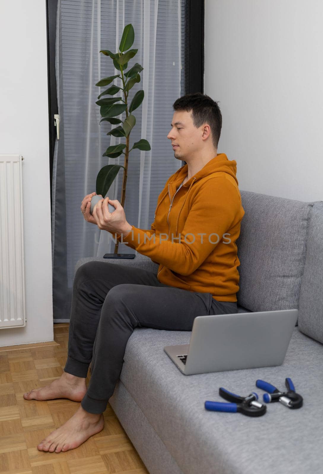 young man exercising at home sitting on couch by Chechotkin