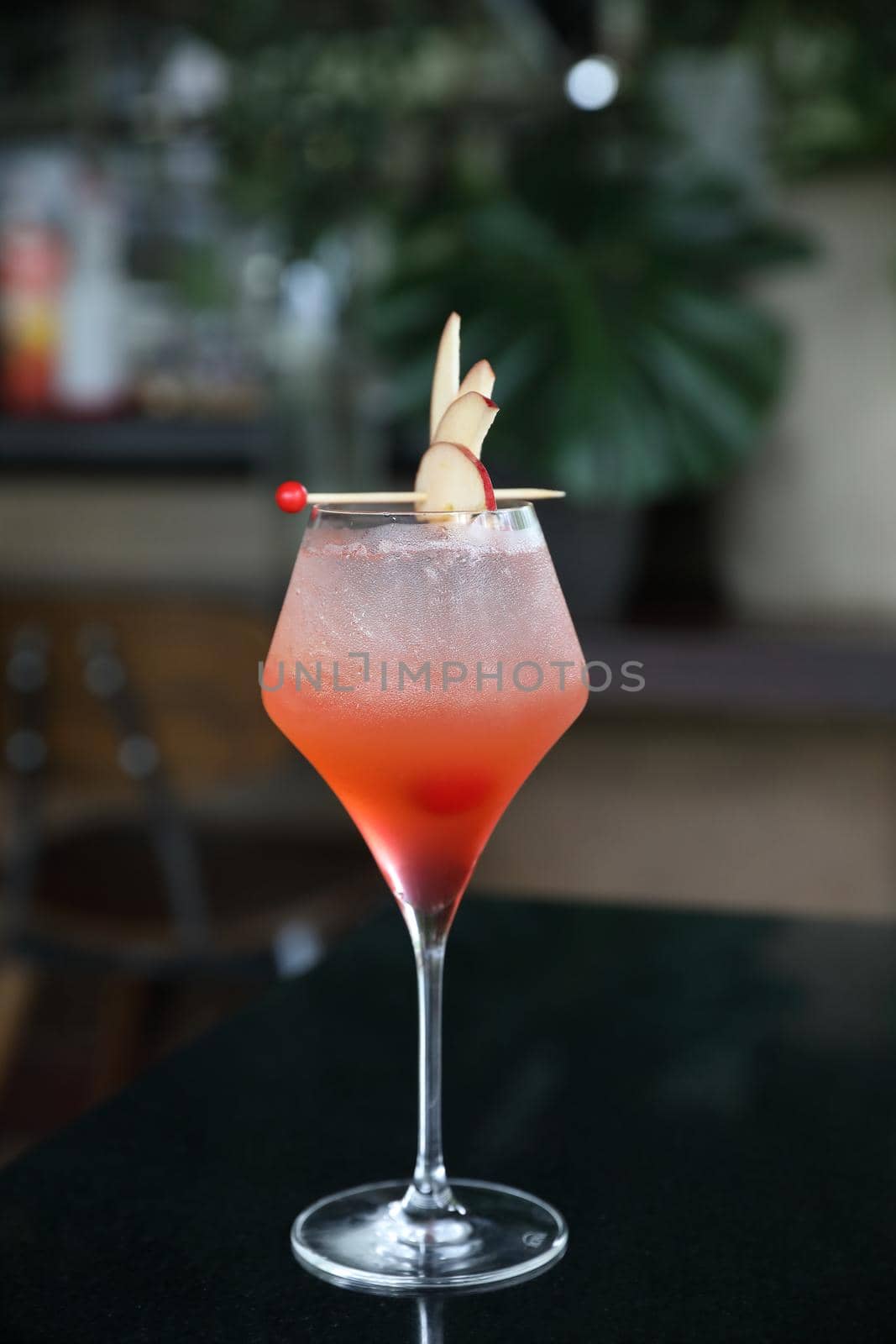 Pink Cocktail glass with ice at a bar counter