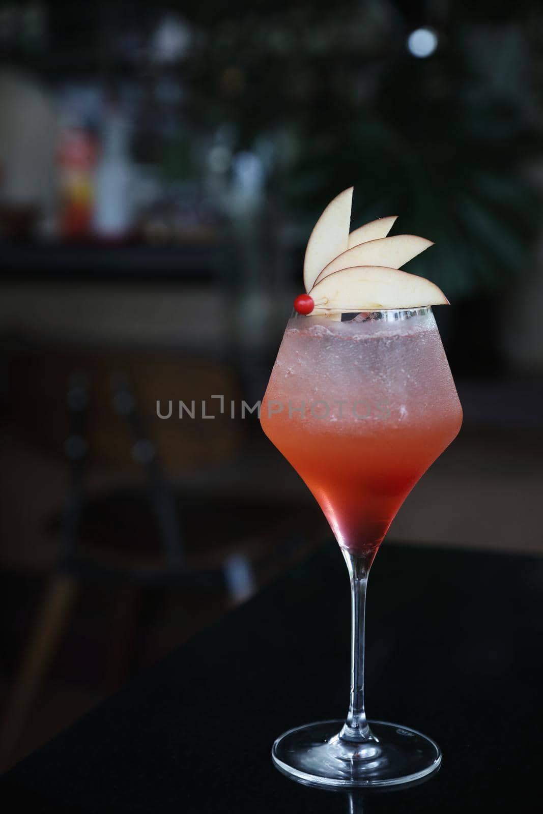 Pink Cocktail glass with ice at a bar counter