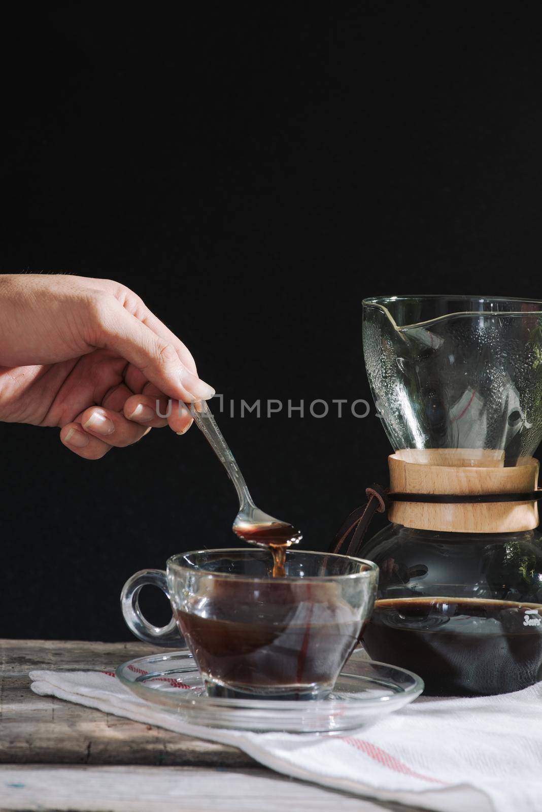 Drip brewing coffee concept. Wooden desk with chocolate cake and cup of coffee on black background.  by makidotvn