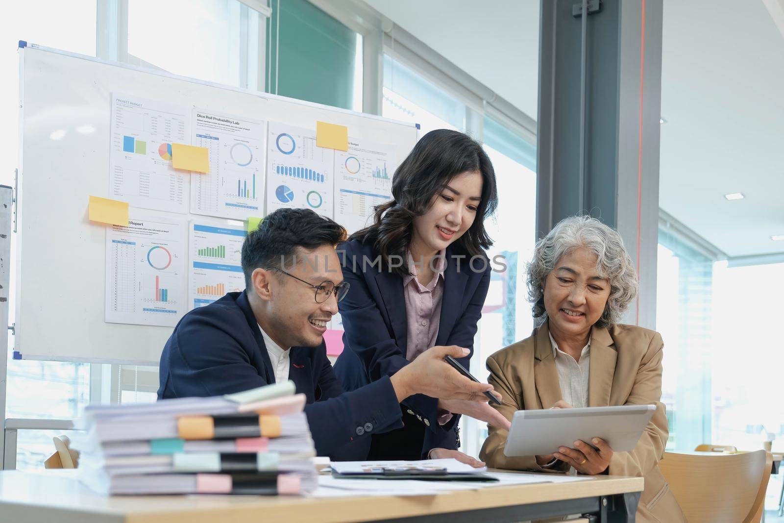 Professional Asian senior businesswoman or female boss in the meeting with her financial analysts team, discussing and analyzing their business financial data together..