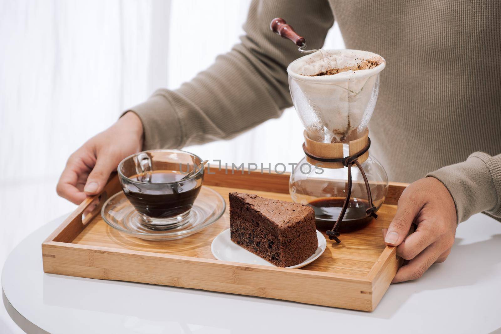 Drip coffee on wooden tray with chocolate cake. Coffee time on the cafe with natural light