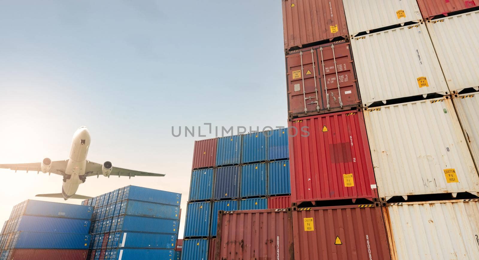 Air logistics. Cargo airplane flying above stack of logistic container. Cargo and shipping business. Container ship for export logistic. Logistic industry from port to port. Freight transportation. by Fahroni