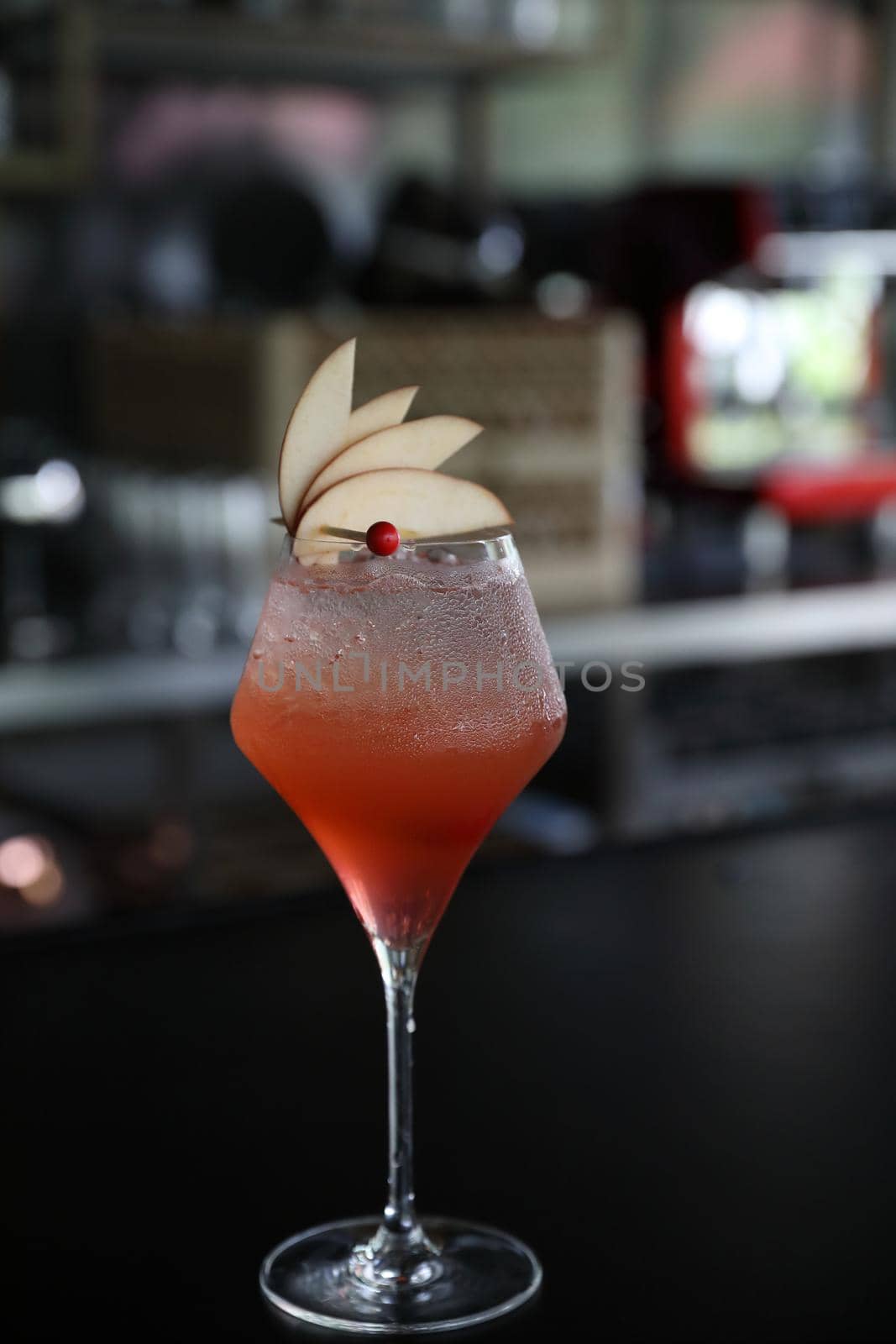 Pink Cocktail glass with ice at a bar counter by piyato