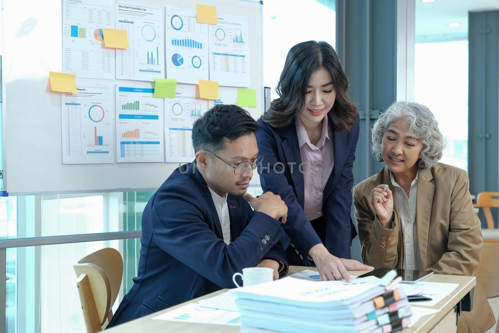 Professional Asian senior businesswoman or female boss in the meeting with her financial analysts team, discussing and analyzing their business financial data together..