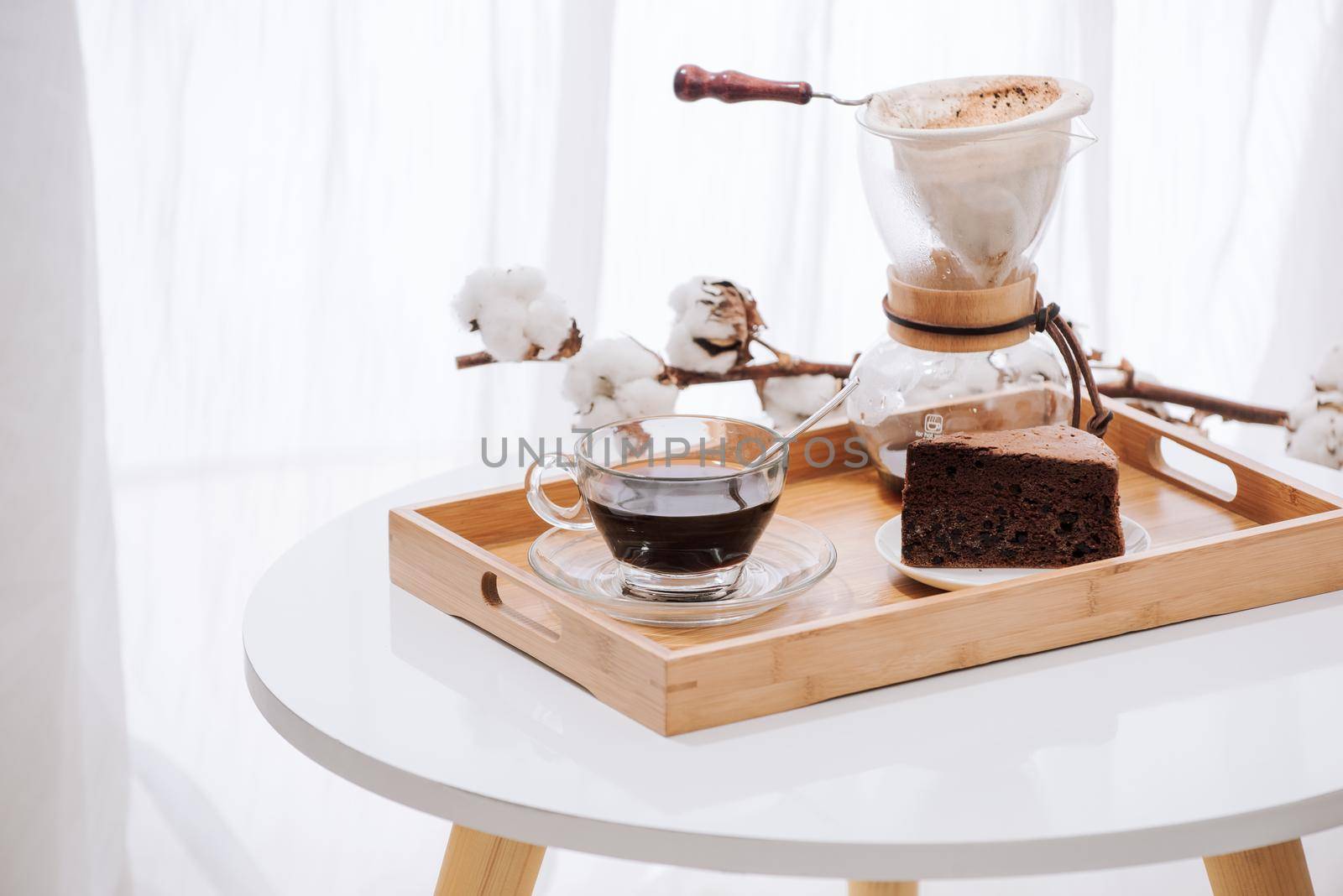 Drip coffee on wooden tray with chocolate cake. Coffee time on the cafe with natural light by makidotvn