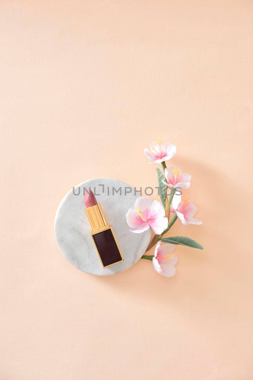 Red lipstick make up and flowers arranged on a pastel purple background with empty space at side by makidotvn