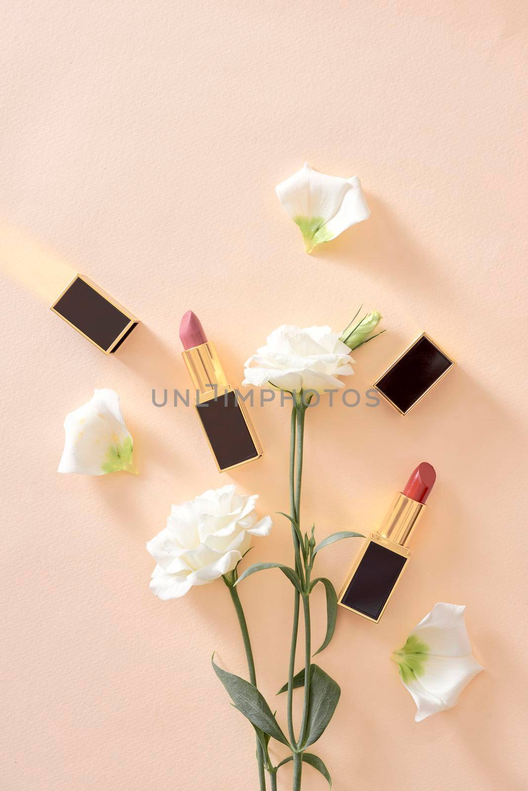 Red lipstick make up and flowers arranged on a pastel purple background with empty space at side