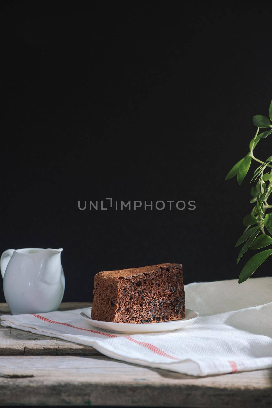 Drip brewing coffee concept. Wooden desk with chocolate cake and cup of coffee on black background.  by makidotvn