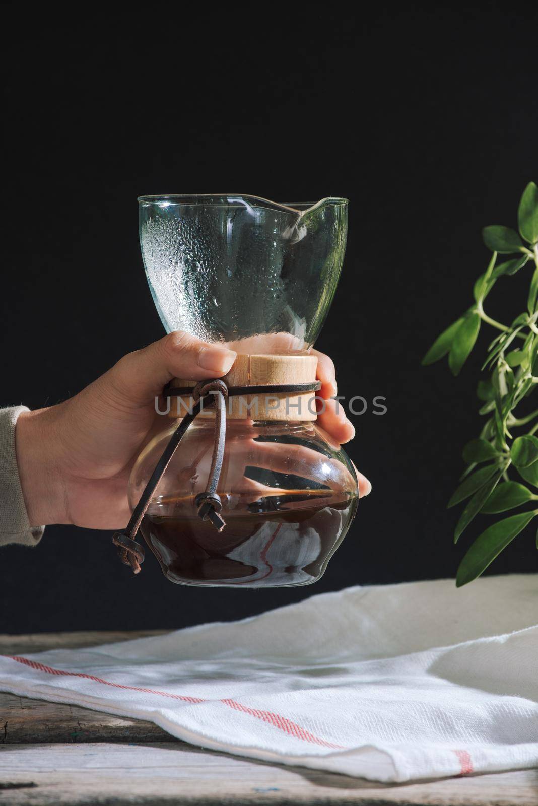 Drip brewing coffee concept. Wooden desk with chocolate cake and cup of coffee on black background. 