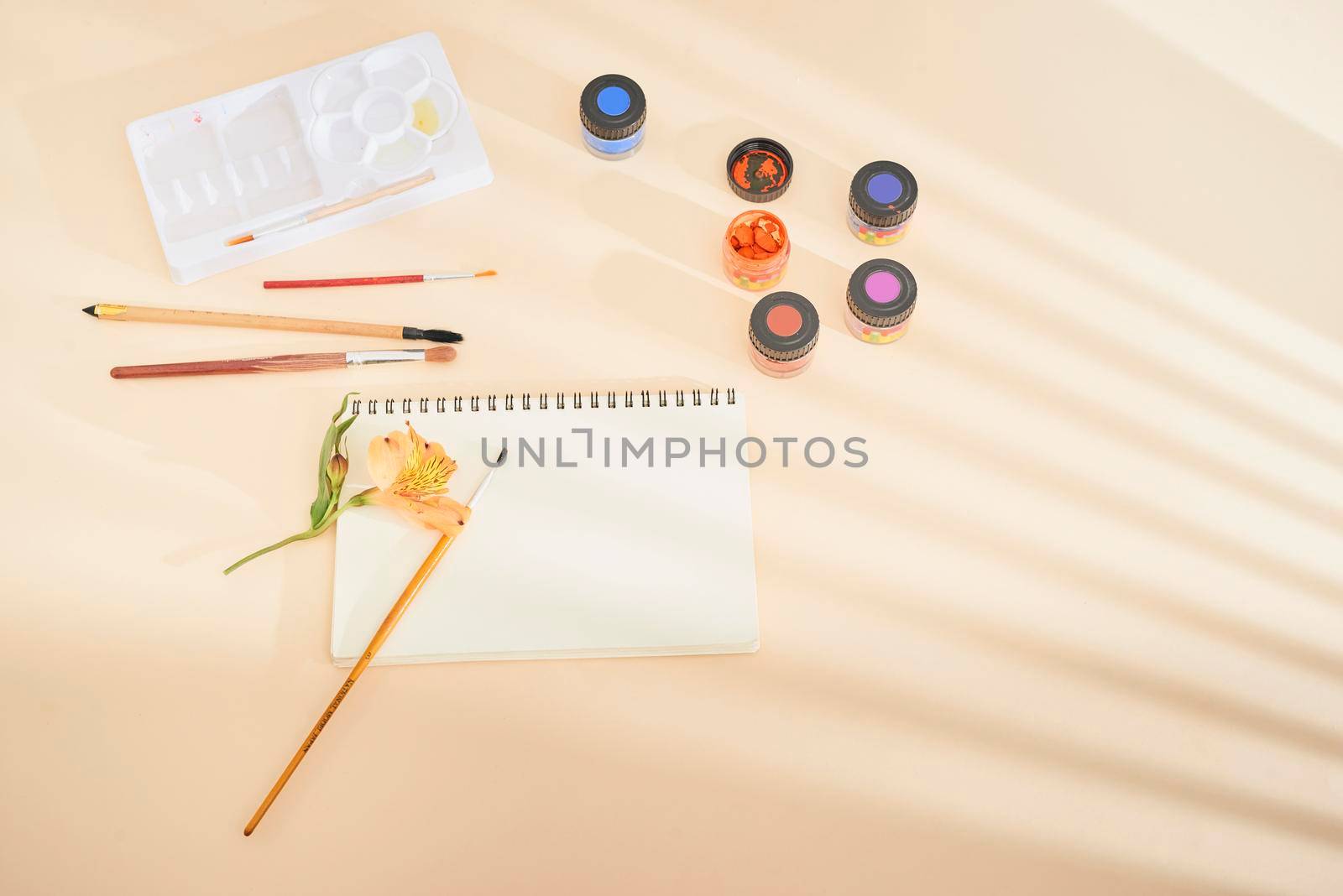 Set of watercolor paint, art brushes and paper on a desk  by makidotvn