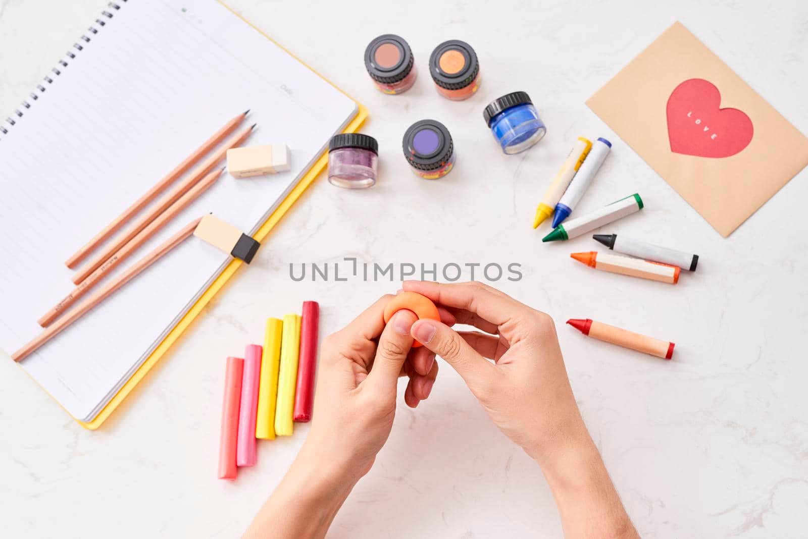 Female hands working with polymer clay. The process of working with the plastic on a white background. by makidotvn