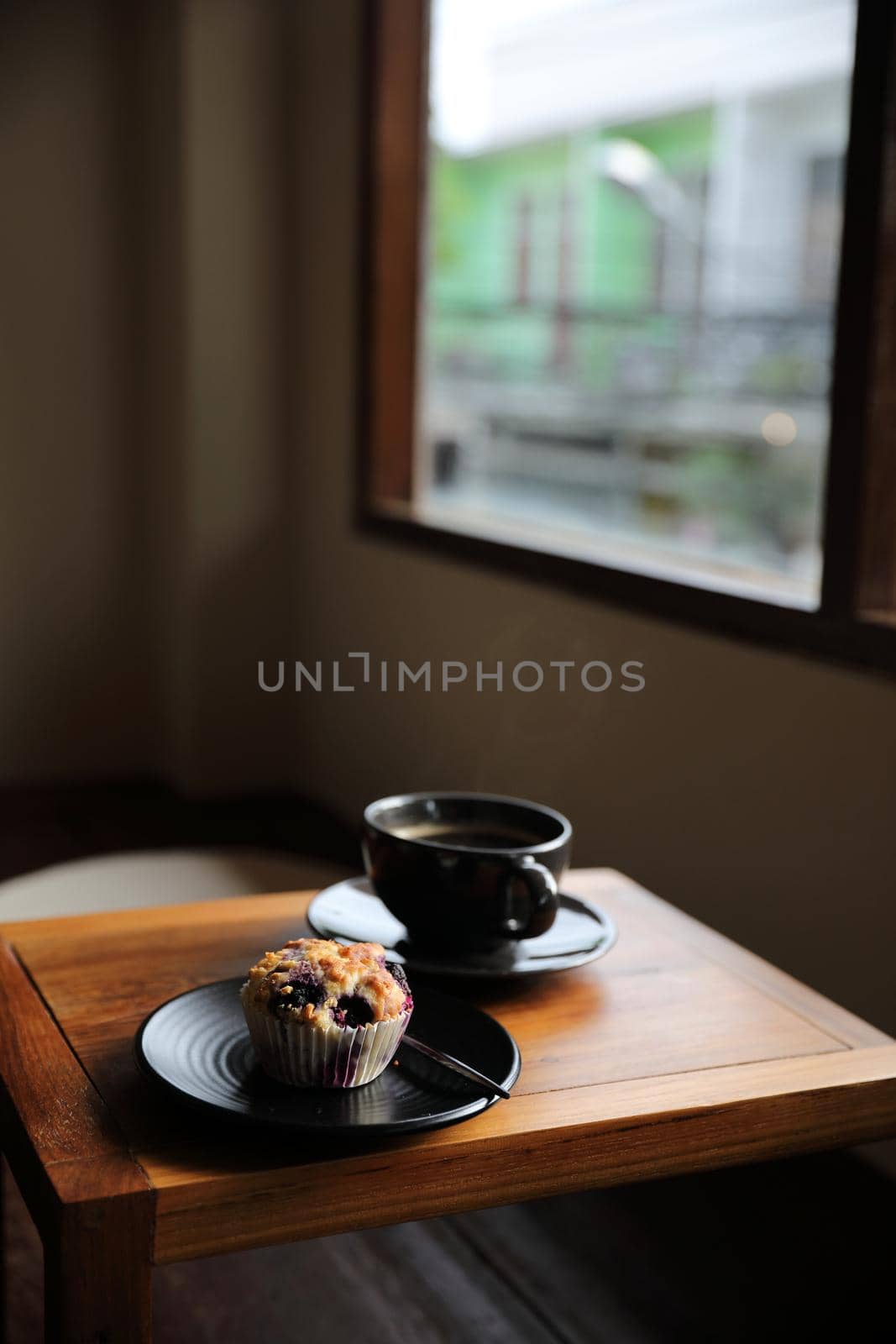 Coffee cup with muffin on wood table in local coffee shop by piyato