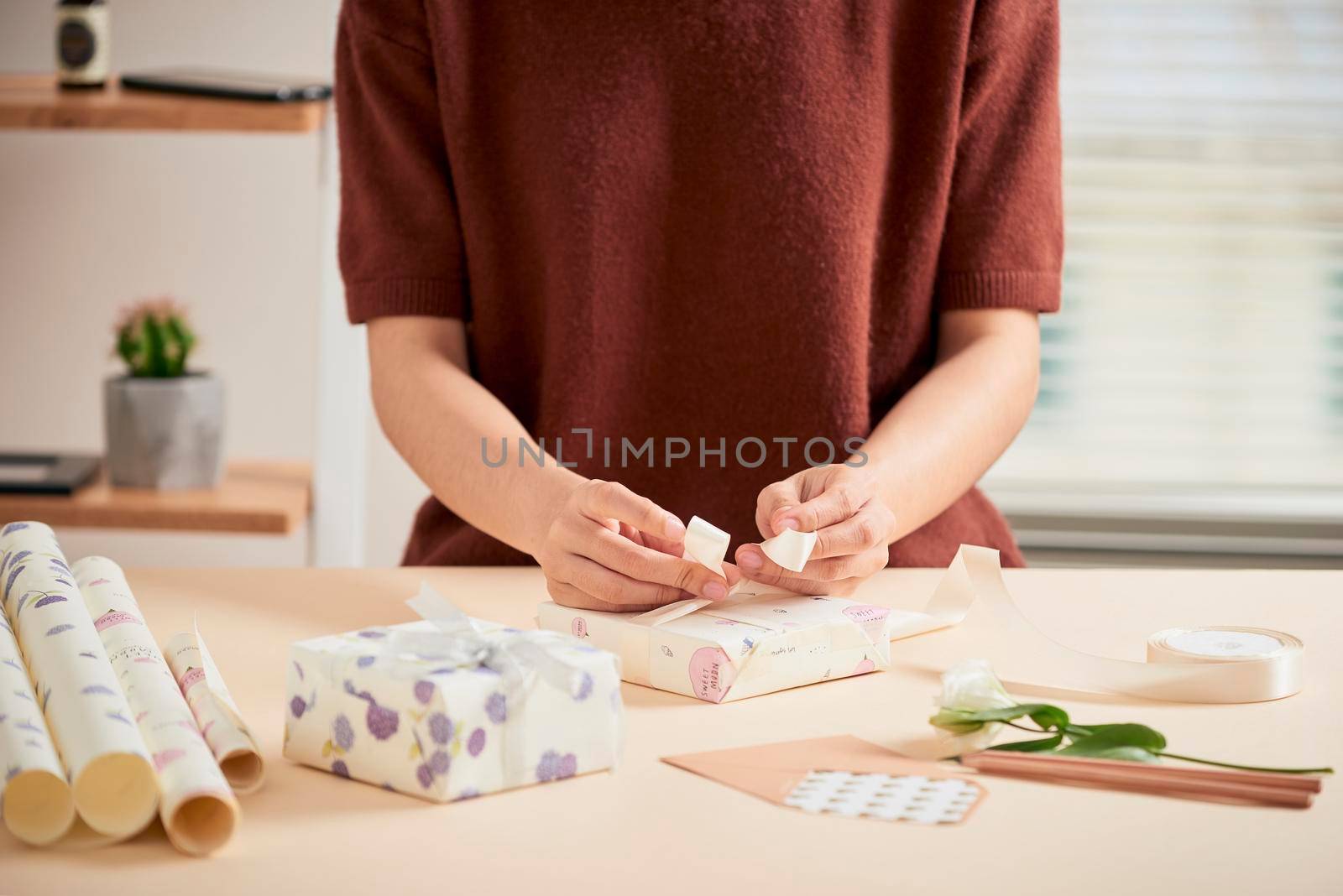 Detail of woman hands packing some presents with gift paper by makidotvn