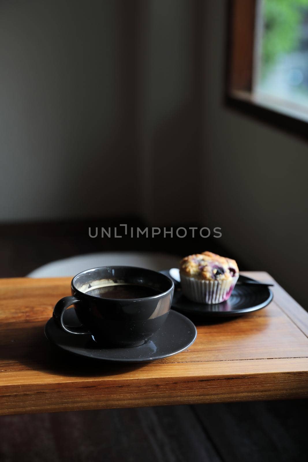 Coffee cup with muffin on wood table in local coffee shop by piyato