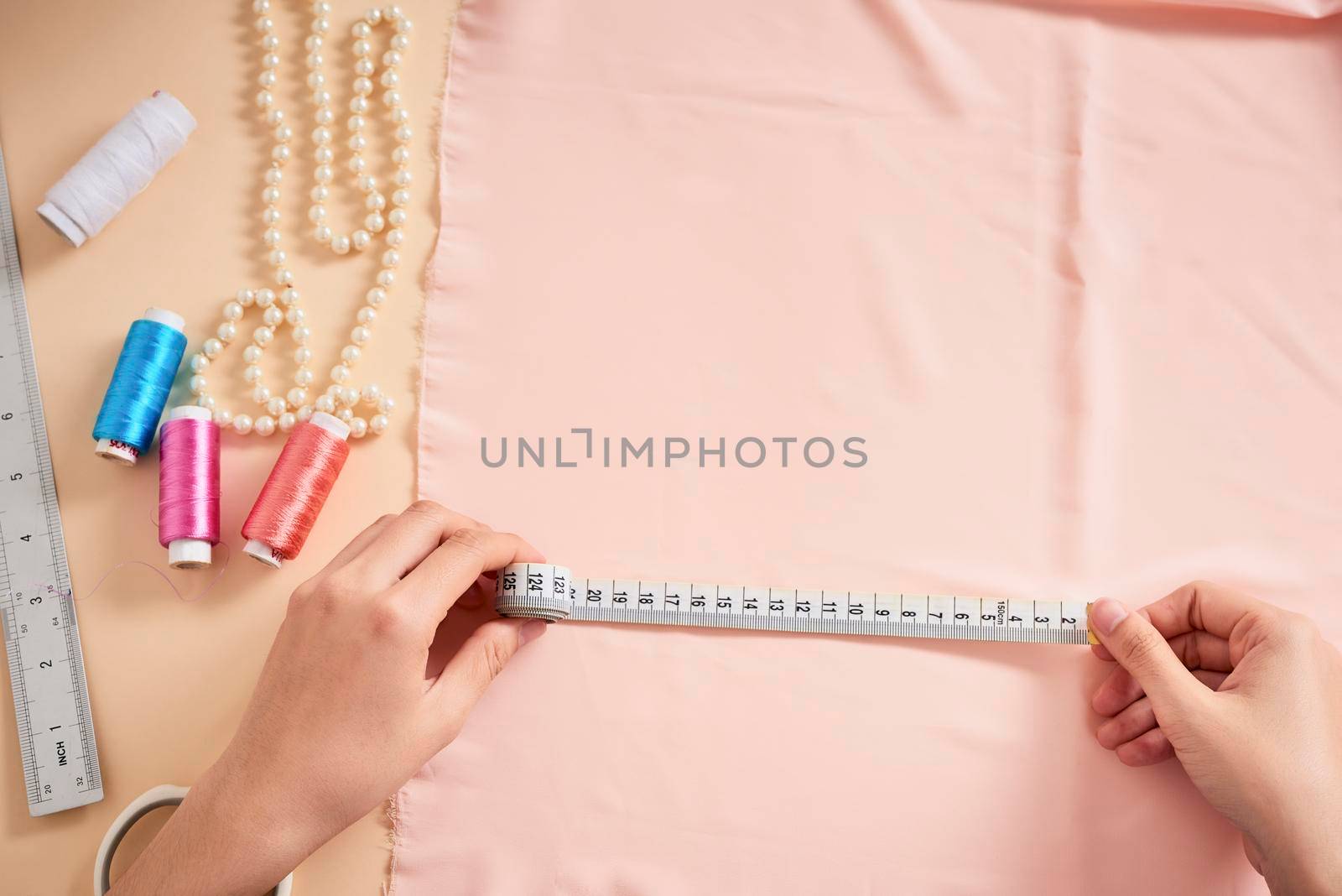 Fashion designer, Woman tailor posing at her workplace with cut fabric, free space on table. Garment industry, tailoring concept