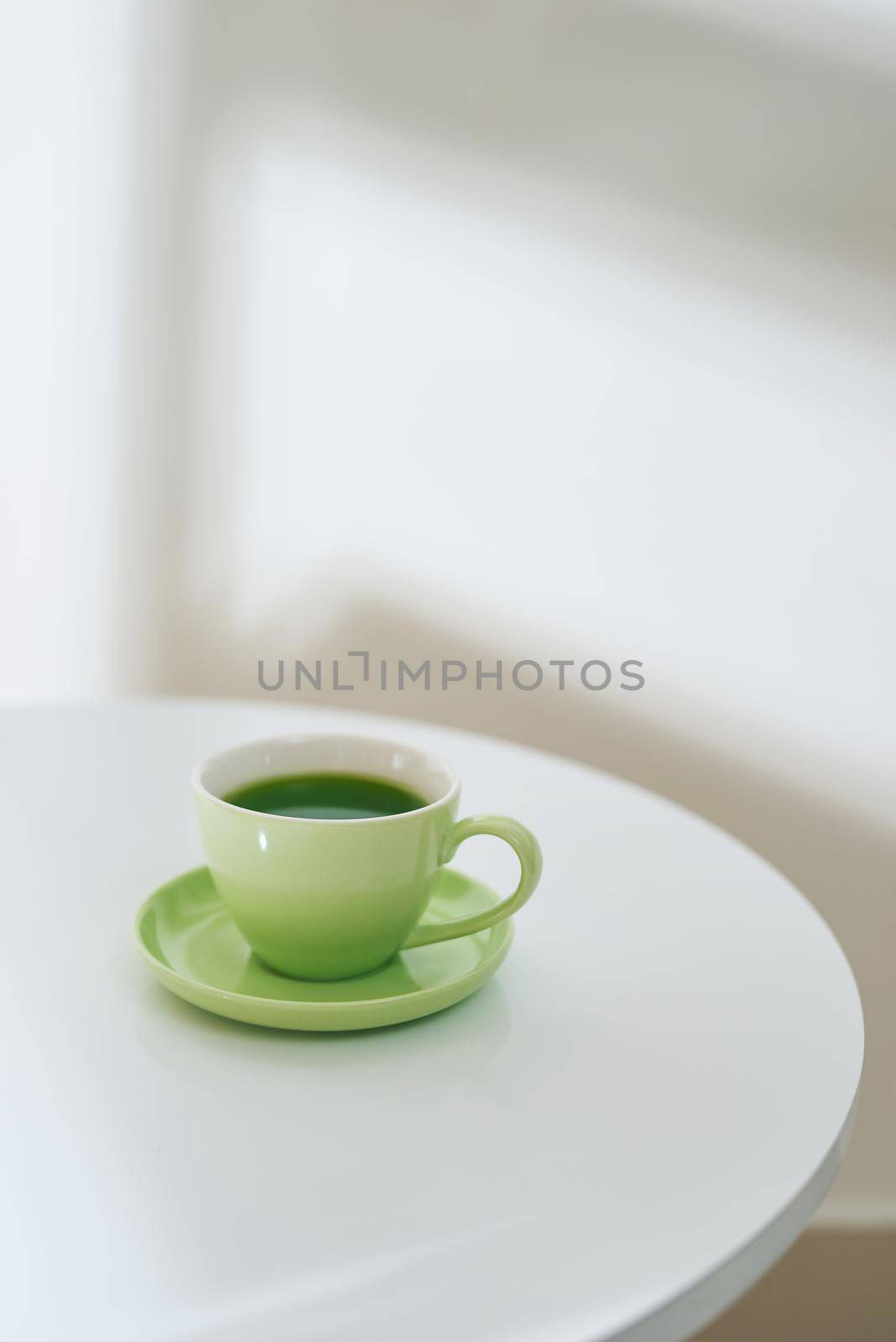 Matcha tea in a green cup on the white table, top view