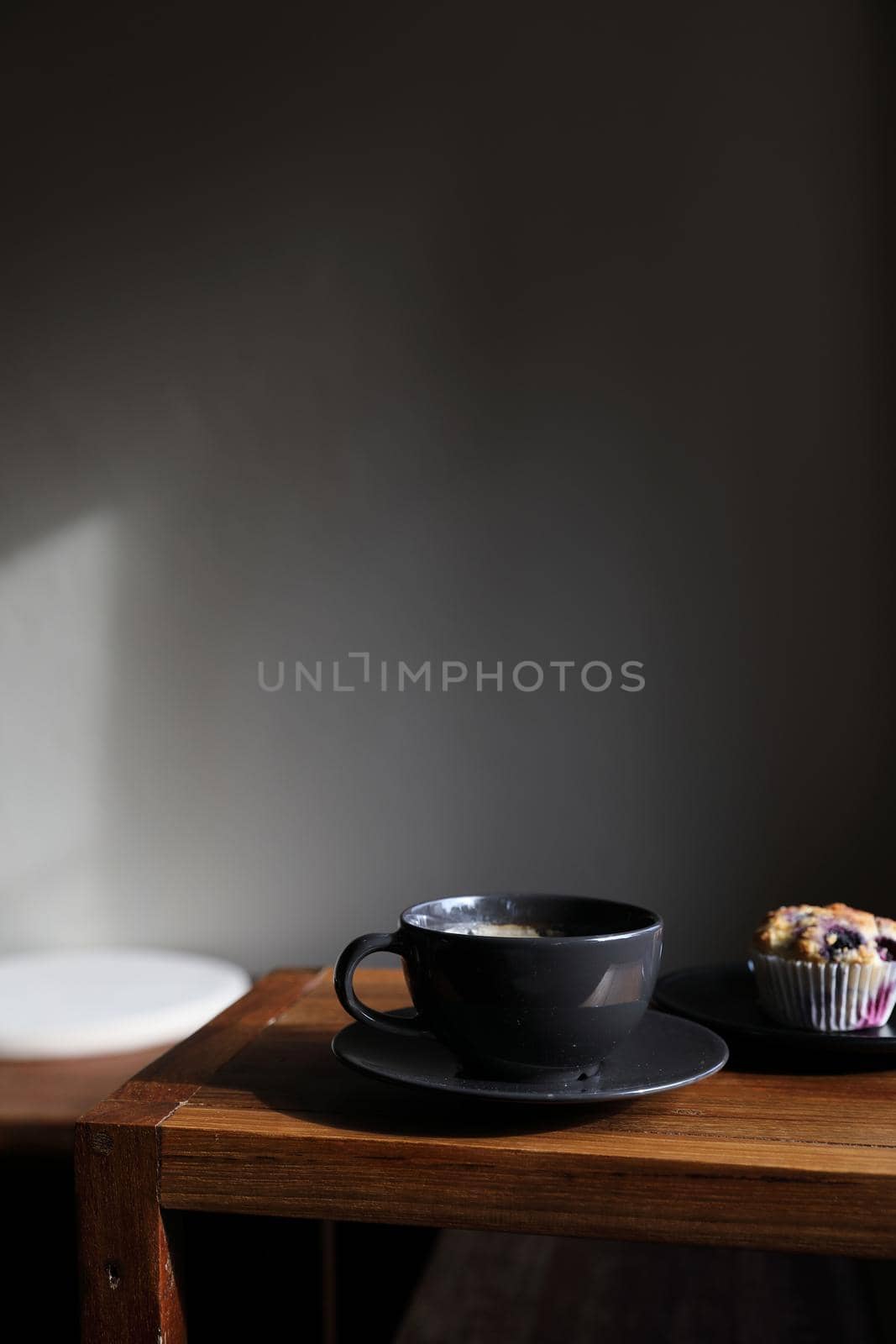 Coffee cup with muffin on wood table in local coffee shop by piyato