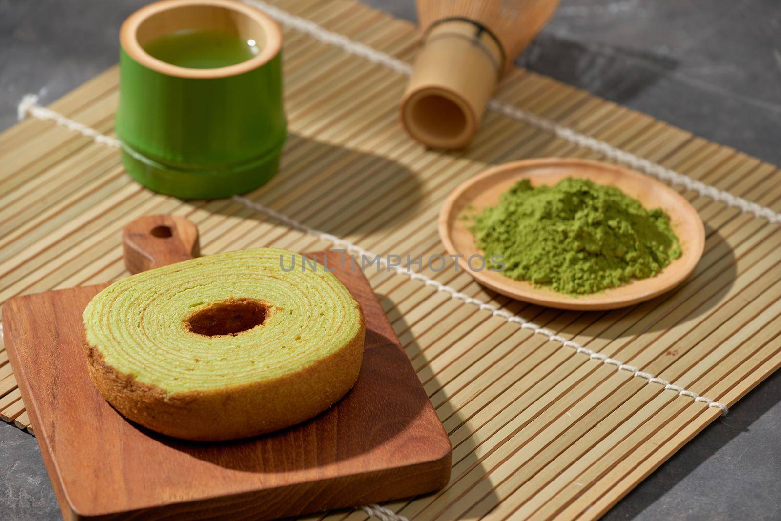 Matcha green tea latte in a cup and tea ceremony utensils with German cake. Copy space by makidotvn