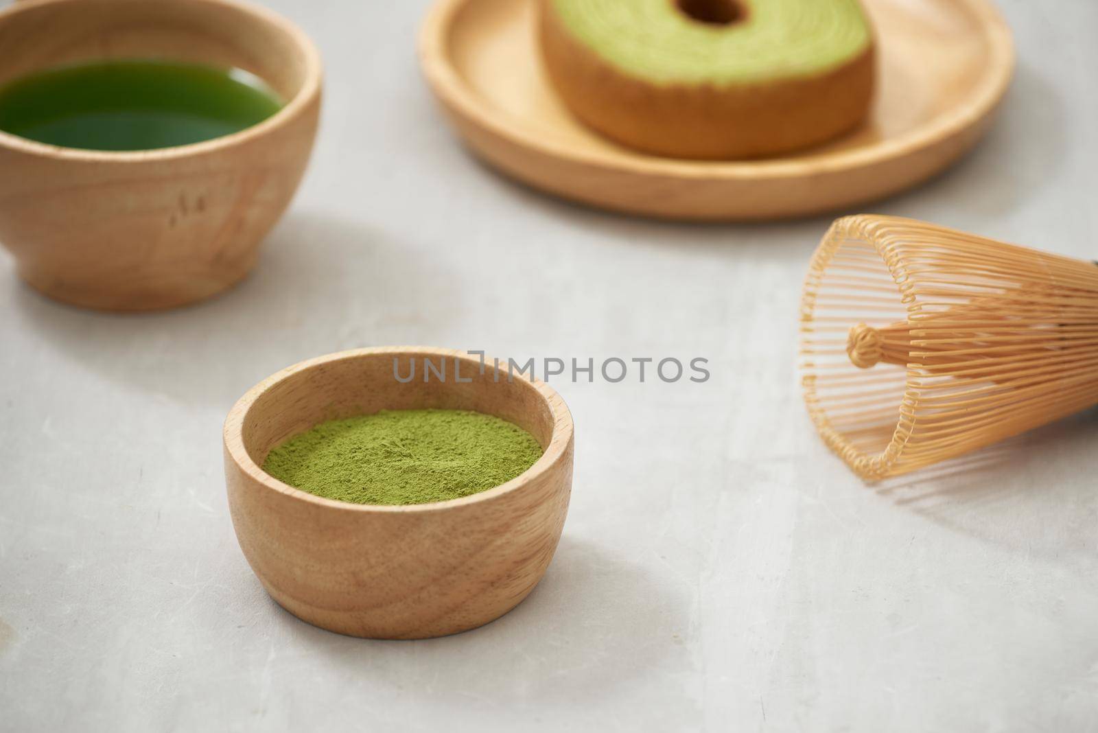 Matcha green tea latte in a cup and tea ceremony utensils with German cake. Copy space