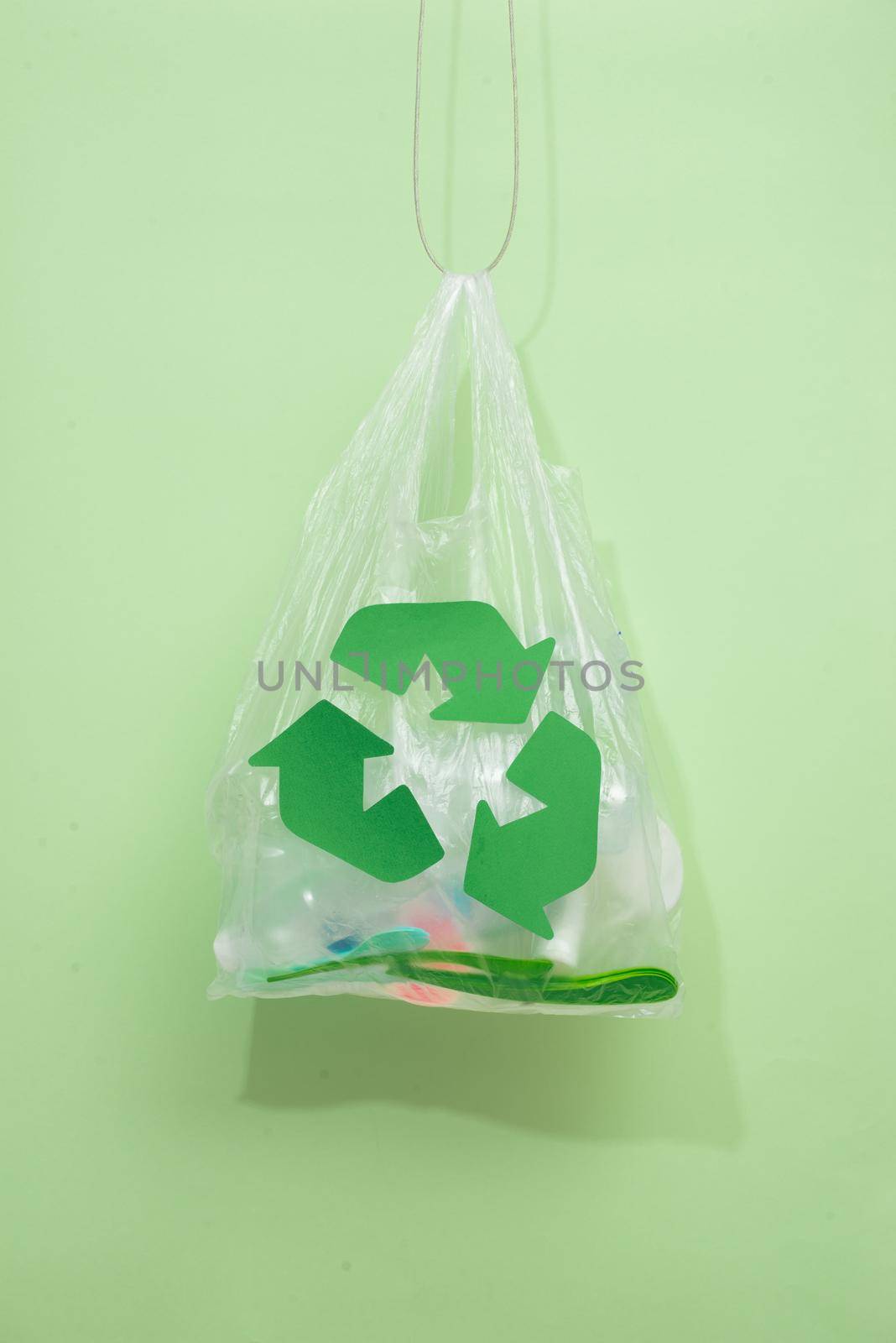 waste recycling, reuse, garbage disposal, environment and ecology concept - close up of rubbish bag with trash or garbage and green recycle symbol at home