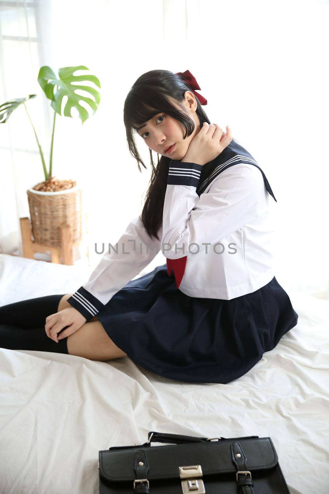 japanese school girl sitting on bedroom in white tone 