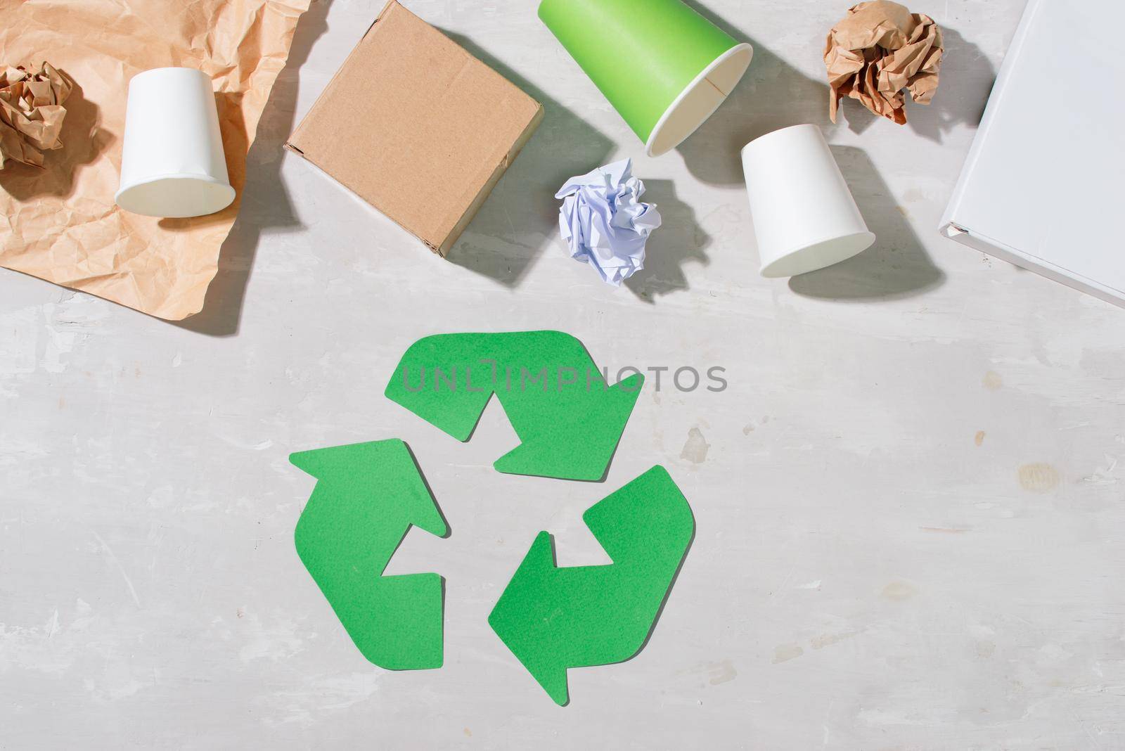 recycling symbol with waste on wooden background top view
