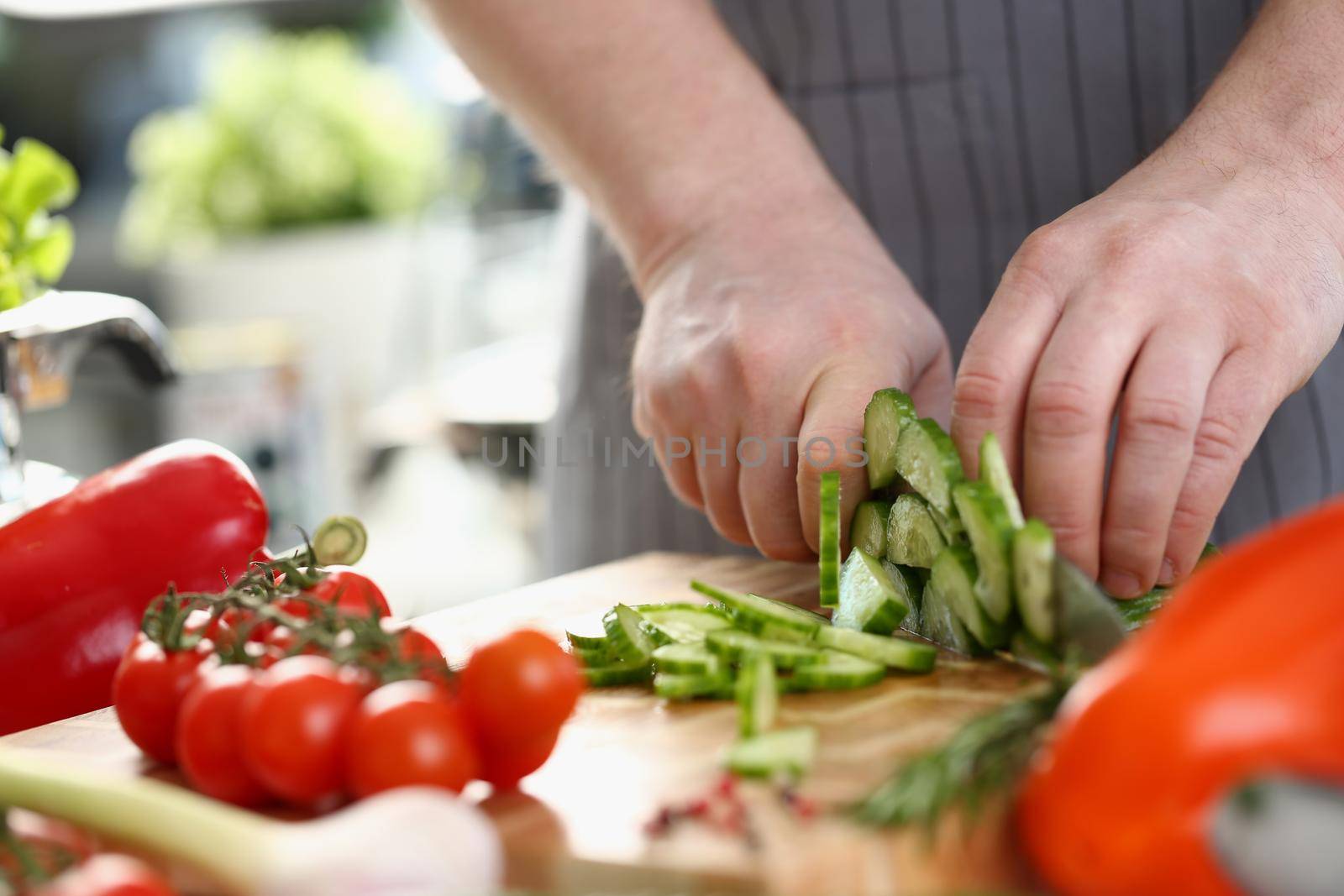 Green cucumbers are cut with knife in kitchen. Healthy food concept vegetable salad and vegetarianism