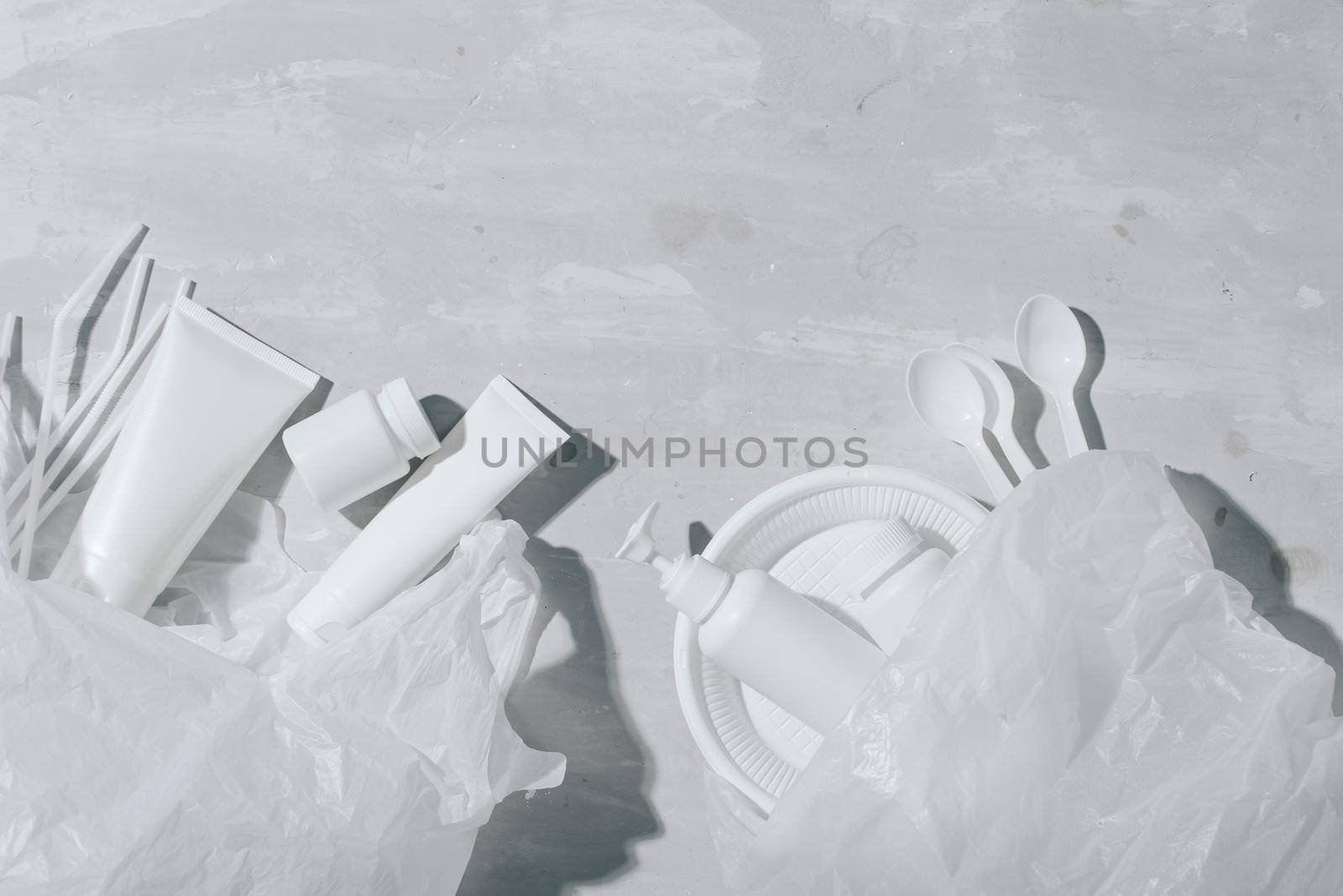 No plastic recycle concept white plastic dishes plates cups spoon on stone background. Copy space. Top view by makidotvn