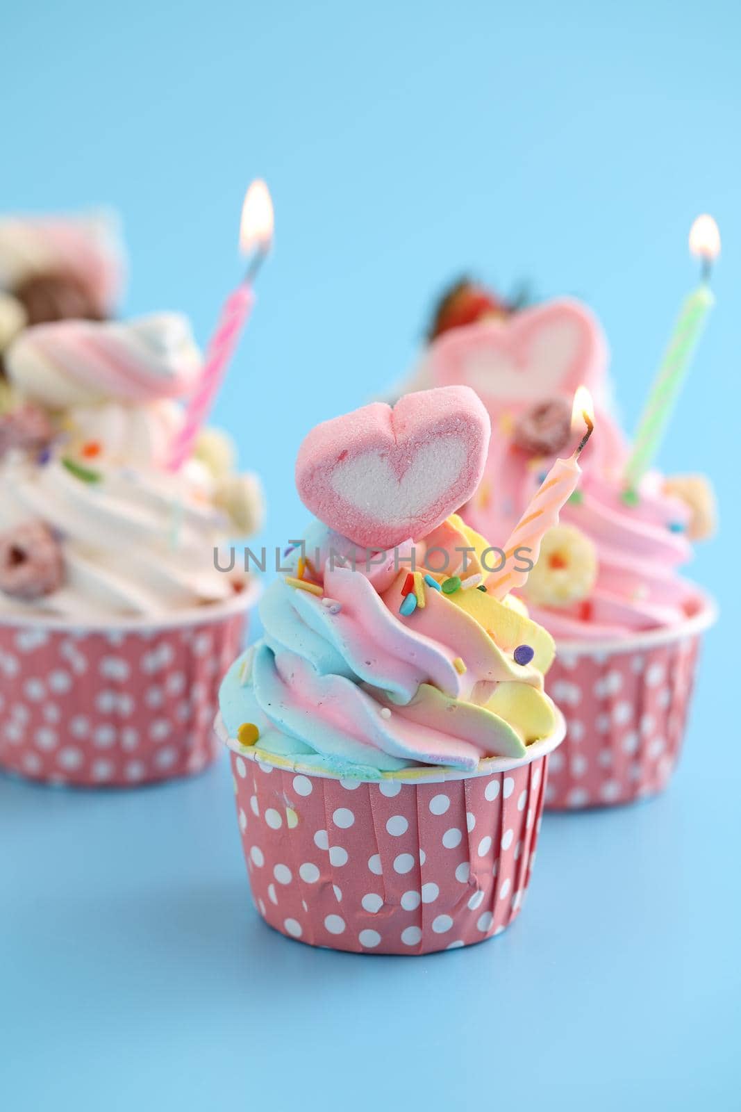 Colorful cupcakes with candle isolated in blue background