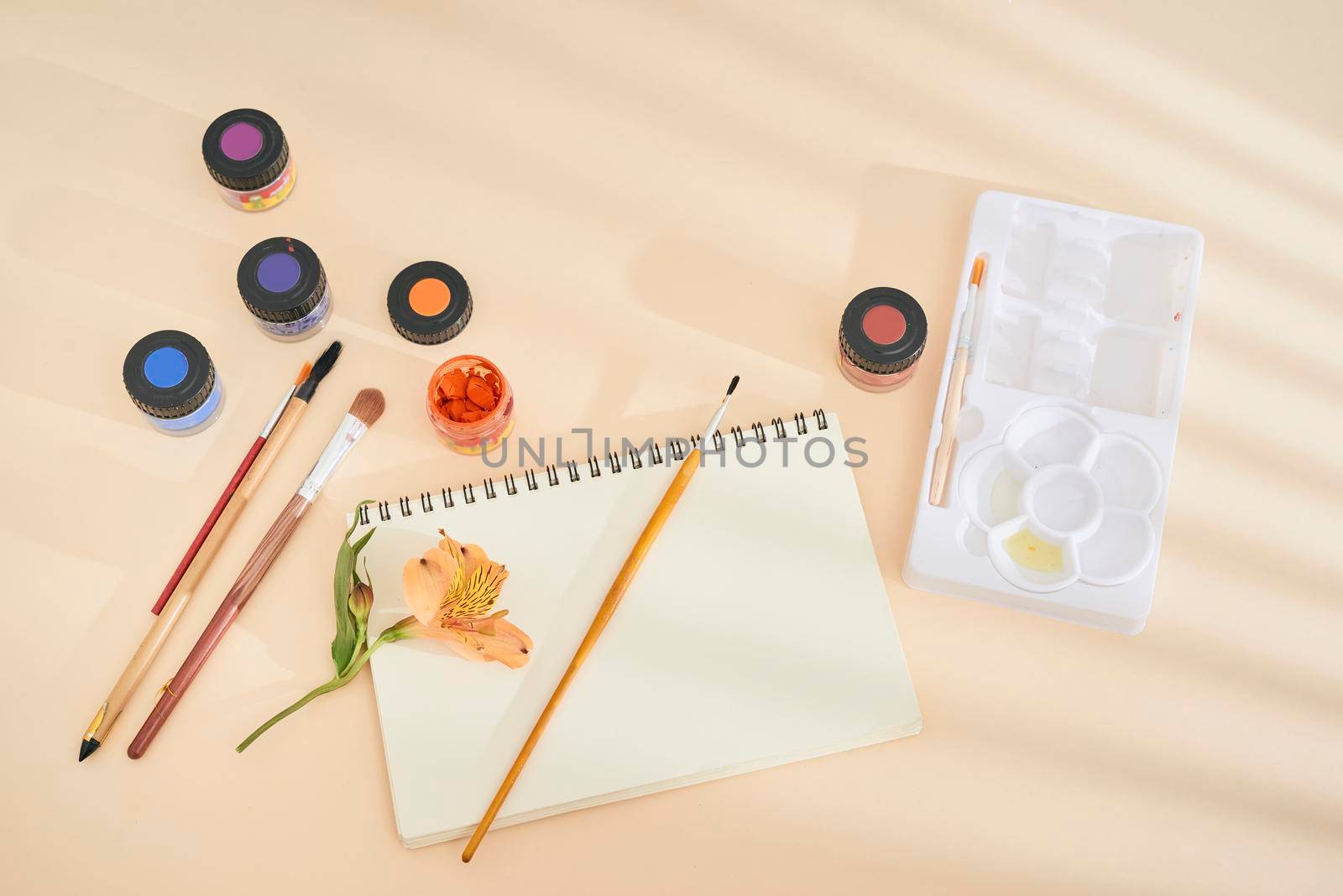 Set of watercolor paint, art brushes and paper on a desk  by makidotvn