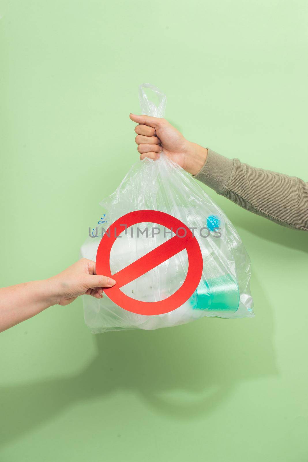 Male hand holding a waste bag isolated on green background. by makidotvn