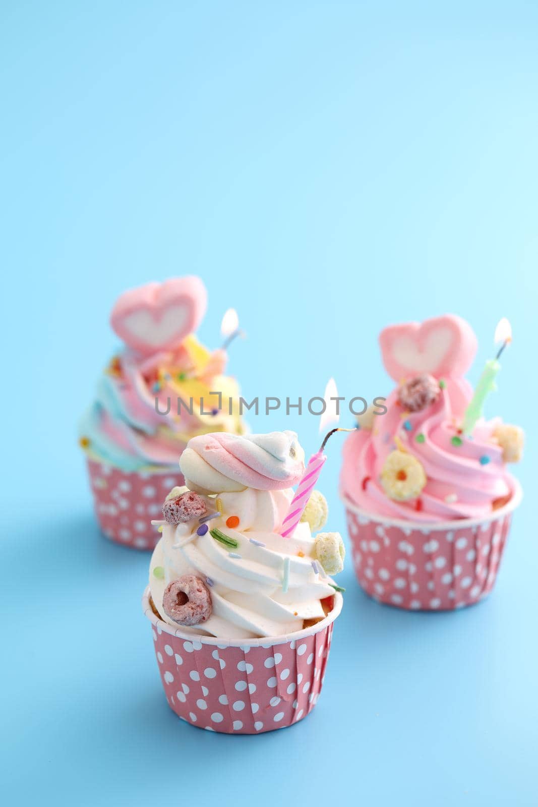 Colorful cupcakes with candle isolated in blue background by piyato