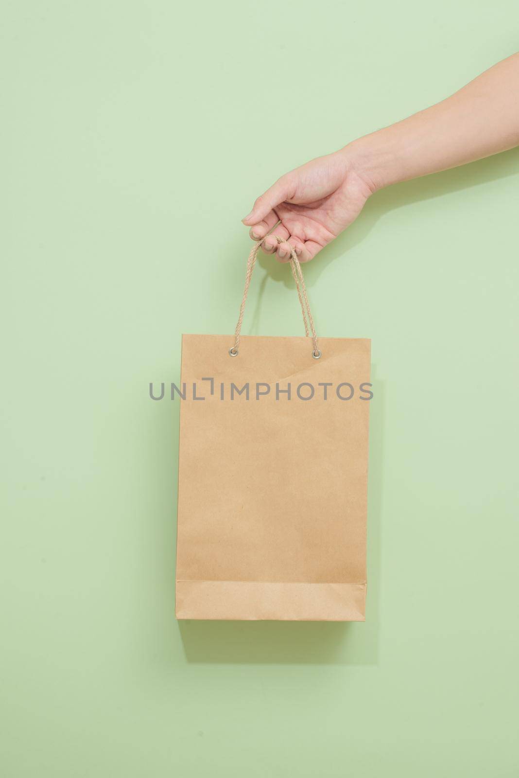 Woman holding paper shopping bag on green background