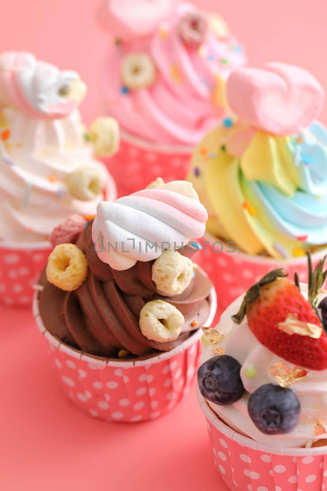 Colorful cupcakes isolated in pink background by piyato