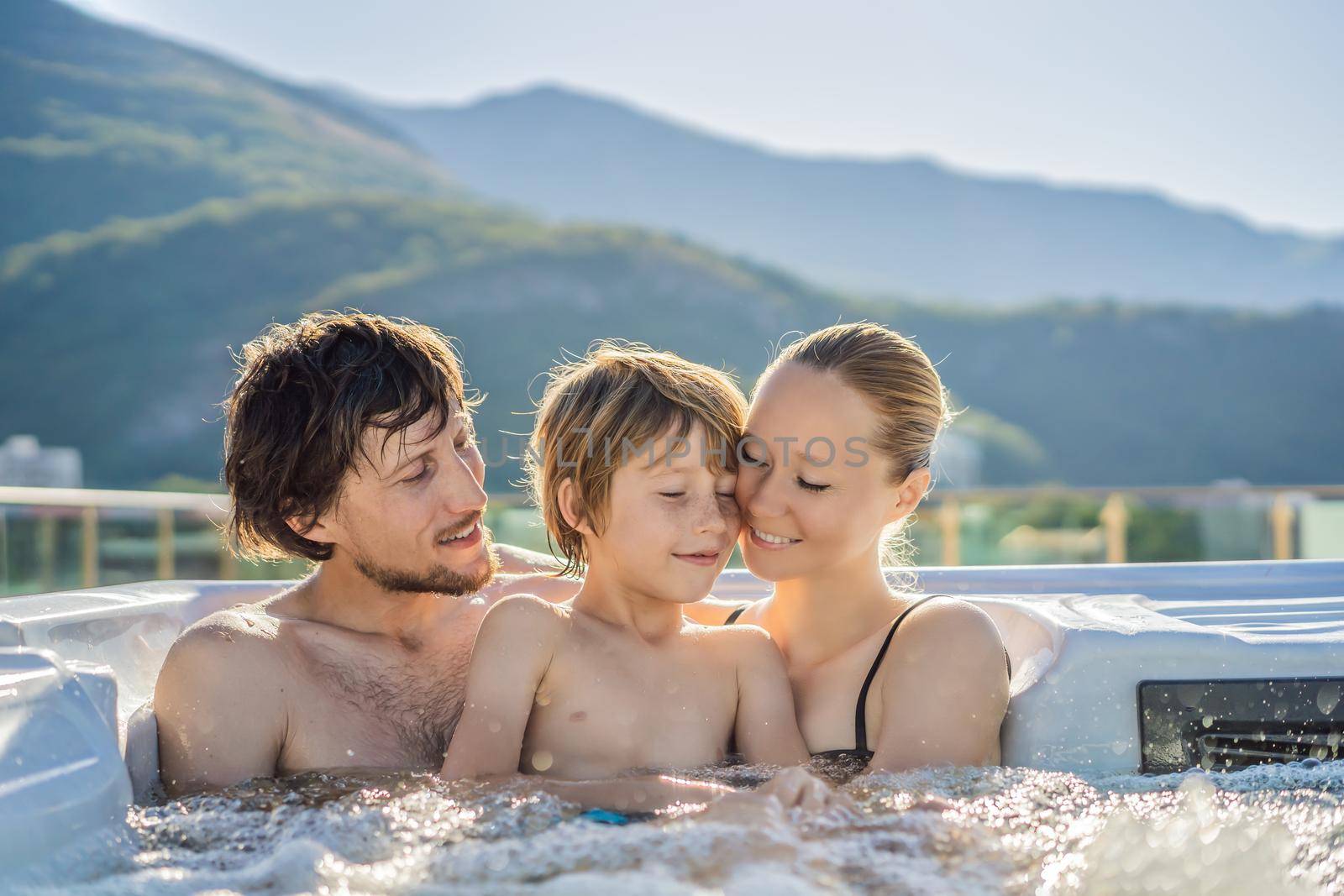 Portrait of young carefree happy smiling happy family relaxing at hot tub during enjoying happy traveling moment vacation. Life against the background of green big mountains.