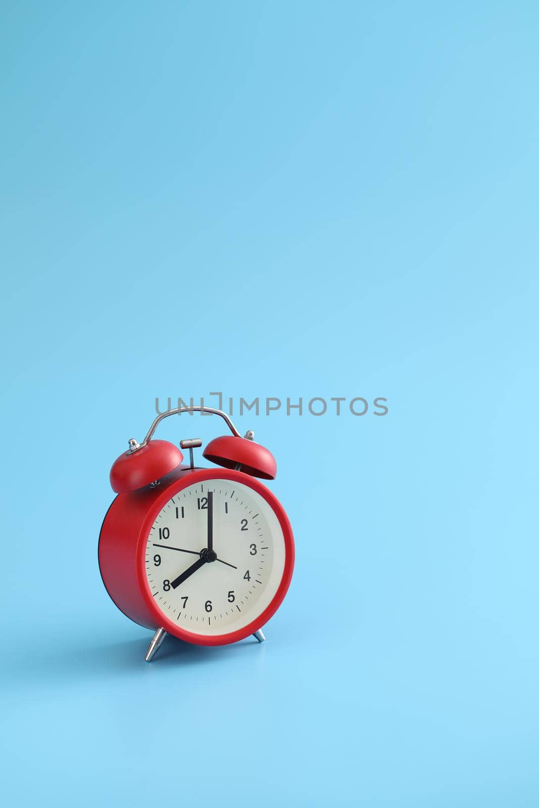 Red retro alarm clock isolated on a blue background by piyato