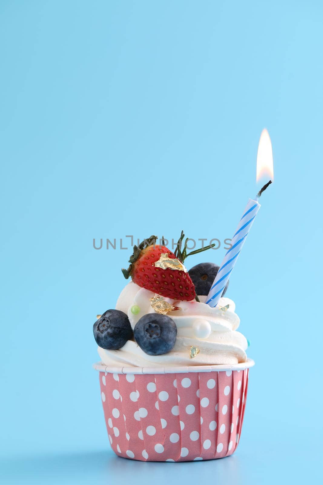 Colorful cupcake with candle isolated in blue background