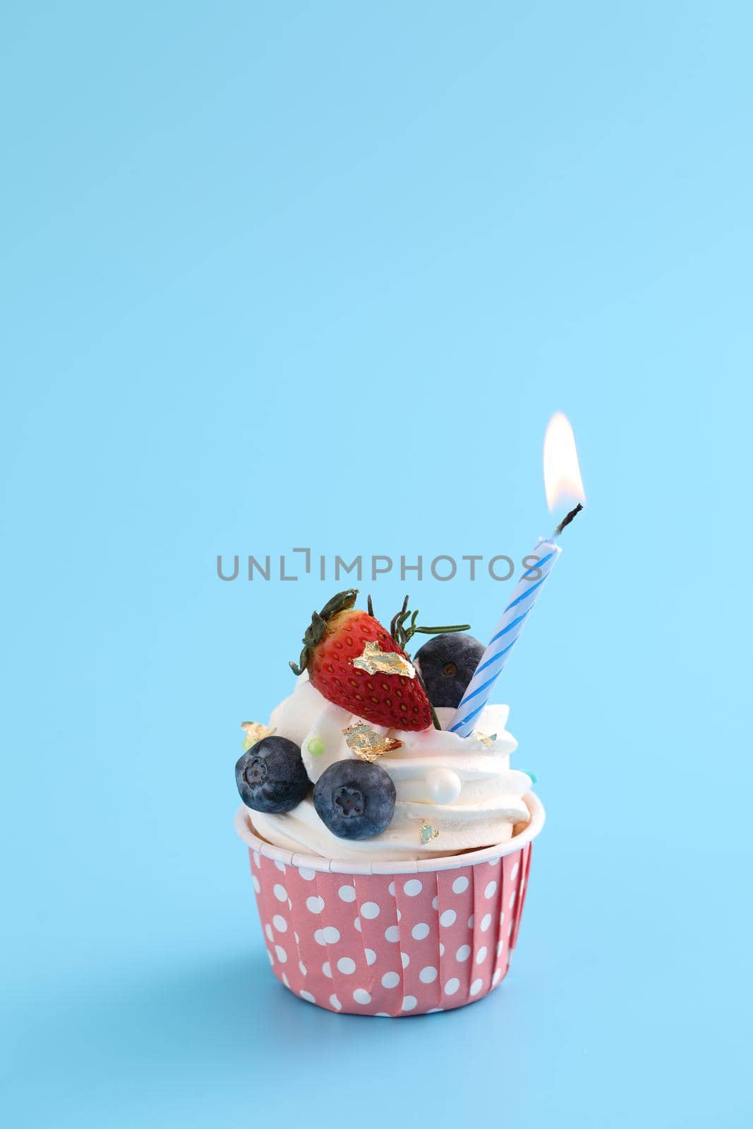 Colorful cupcake with candle isolated in blue background