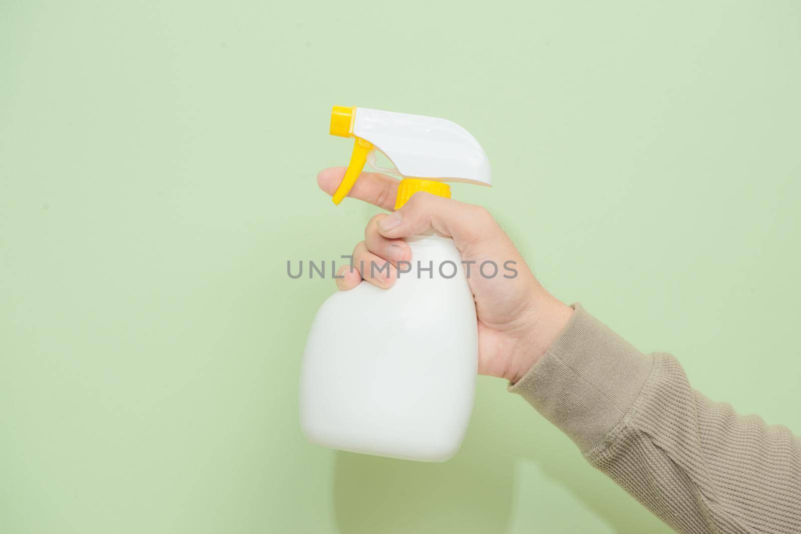 Male hand with sprayer isolated on green background by makidotvn