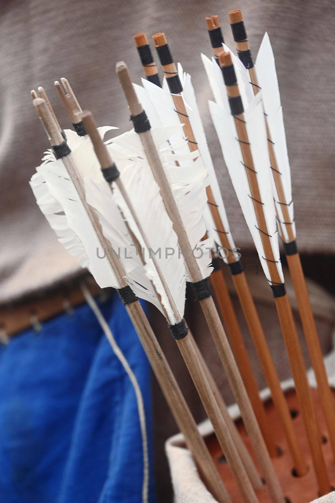 Wooden arrows for the bow. Hand crafted arrows in medieval style. Arrows with feather plumage in archer's quiver. Historical reconstruction - arrows for the bow. Medieval set of archer.