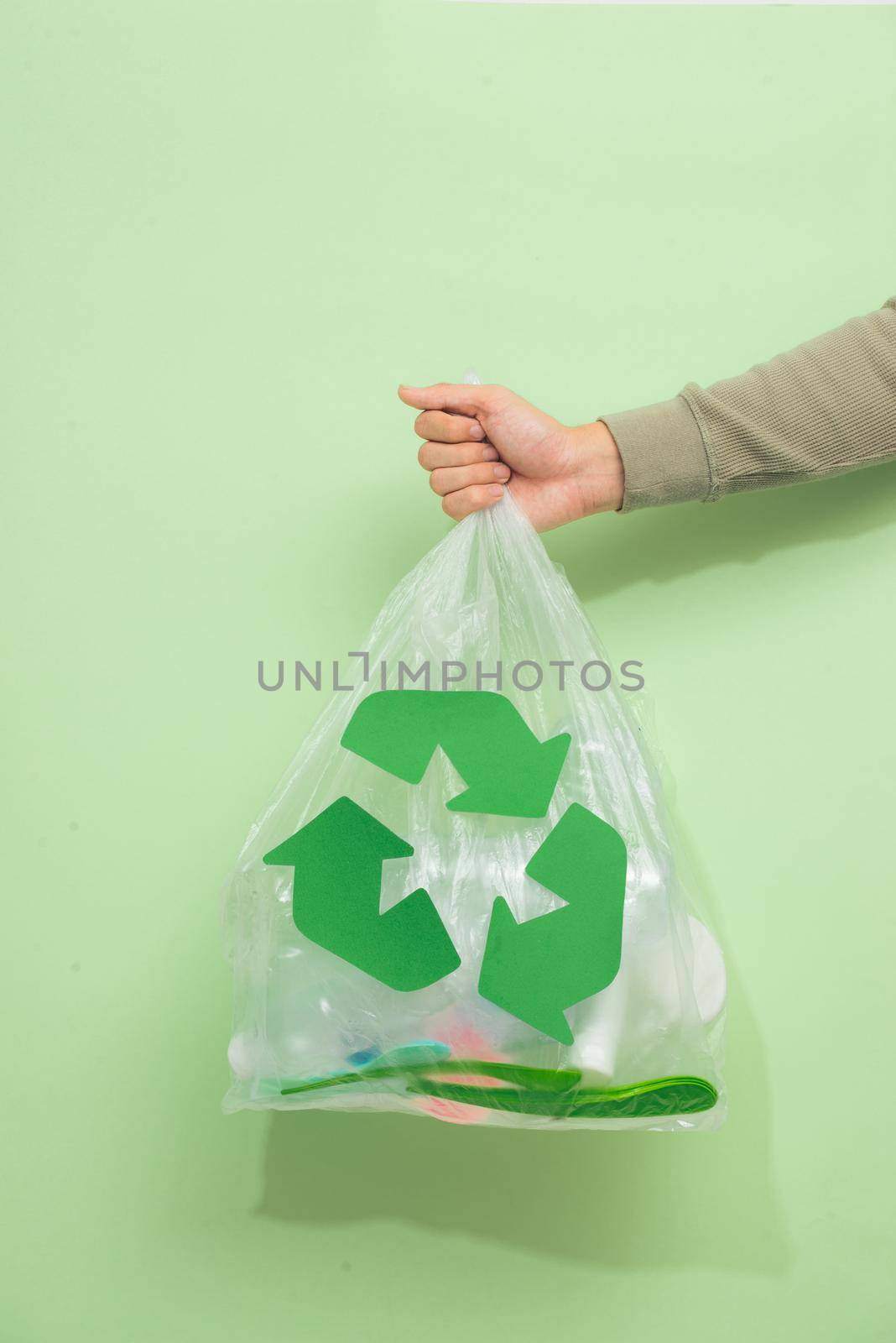 waste recycling, reuse, garbage disposal, environment and ecology concept - close up of rubbish bag with trash or garbage and green recycle symbol at home