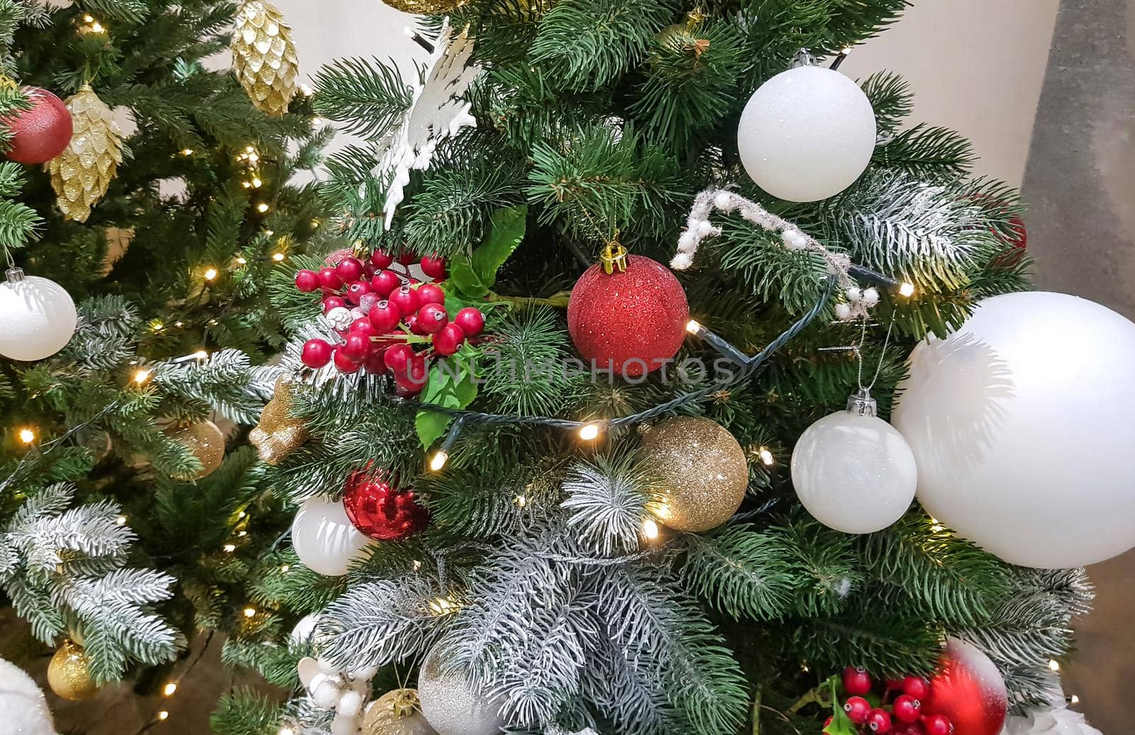 Close-up of fir branches decorated with garlands, balloons and frozen berries, beautiful Christmas background.